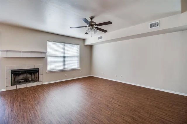 an empty room with wooden floor fireplace and windows
