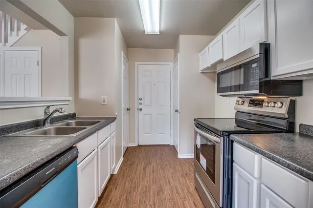 a kitchen with granite countertop a sink stove and cabinets