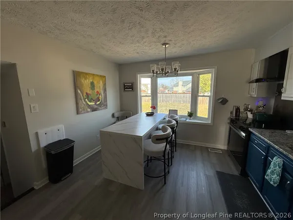 a kitchen with granite countertop a sink appliances wooden floor and a window