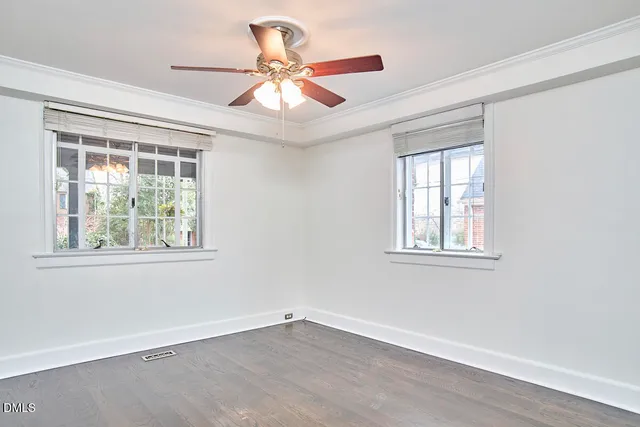 an empty room with wooden floor chandelier fan and windows