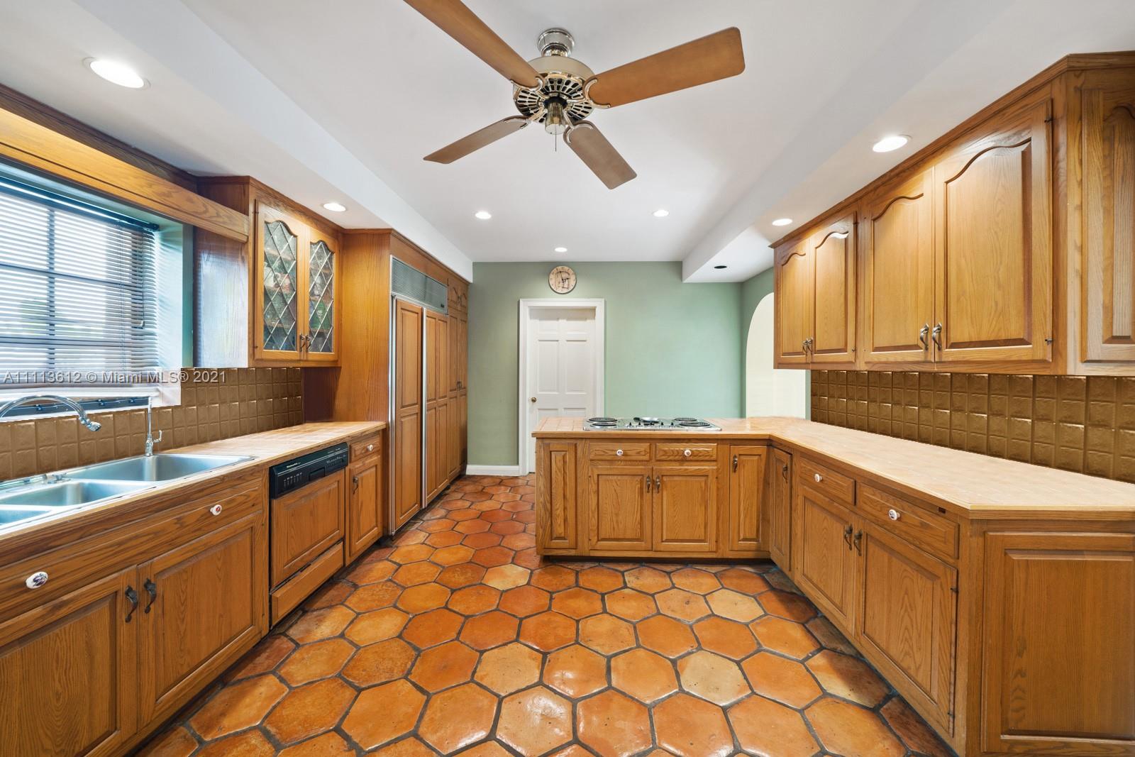 1333 Blue Road Coral Gables, FL 33146 - Photo 13 of 25 a large kitchen with stainless steel appliances kitchen island granite countertop a sink and cabinets