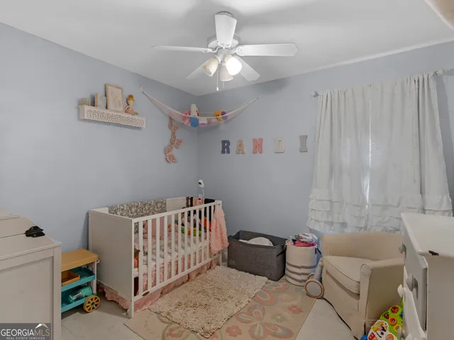 a bedroom with a baby bed a couch and a chandelier