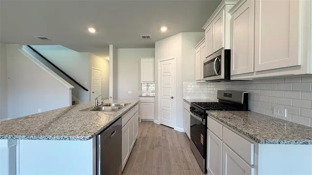 a kitchen with sink stove microwave and refrigerator