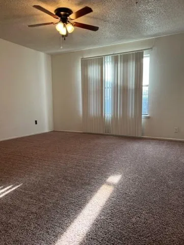 an empty room with chandelier fan and windows