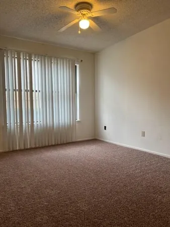 an empty room with windows and chandelier fan