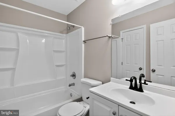 a bathroom with a bathtub shower sink vanity mirror and toilet
