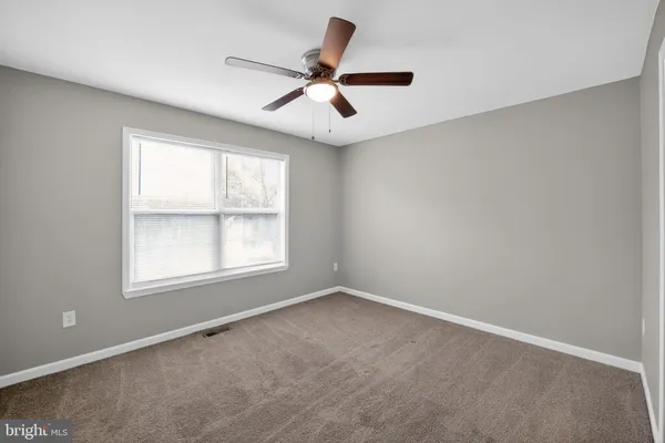 an empty room with a window and a fan