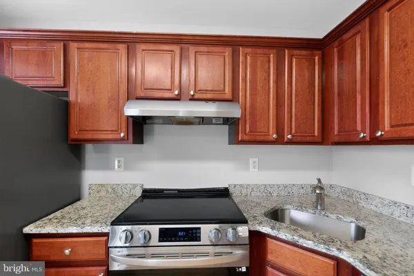 a kitchen with granite countertop stainless steel appliances wooden cabinets and a sink