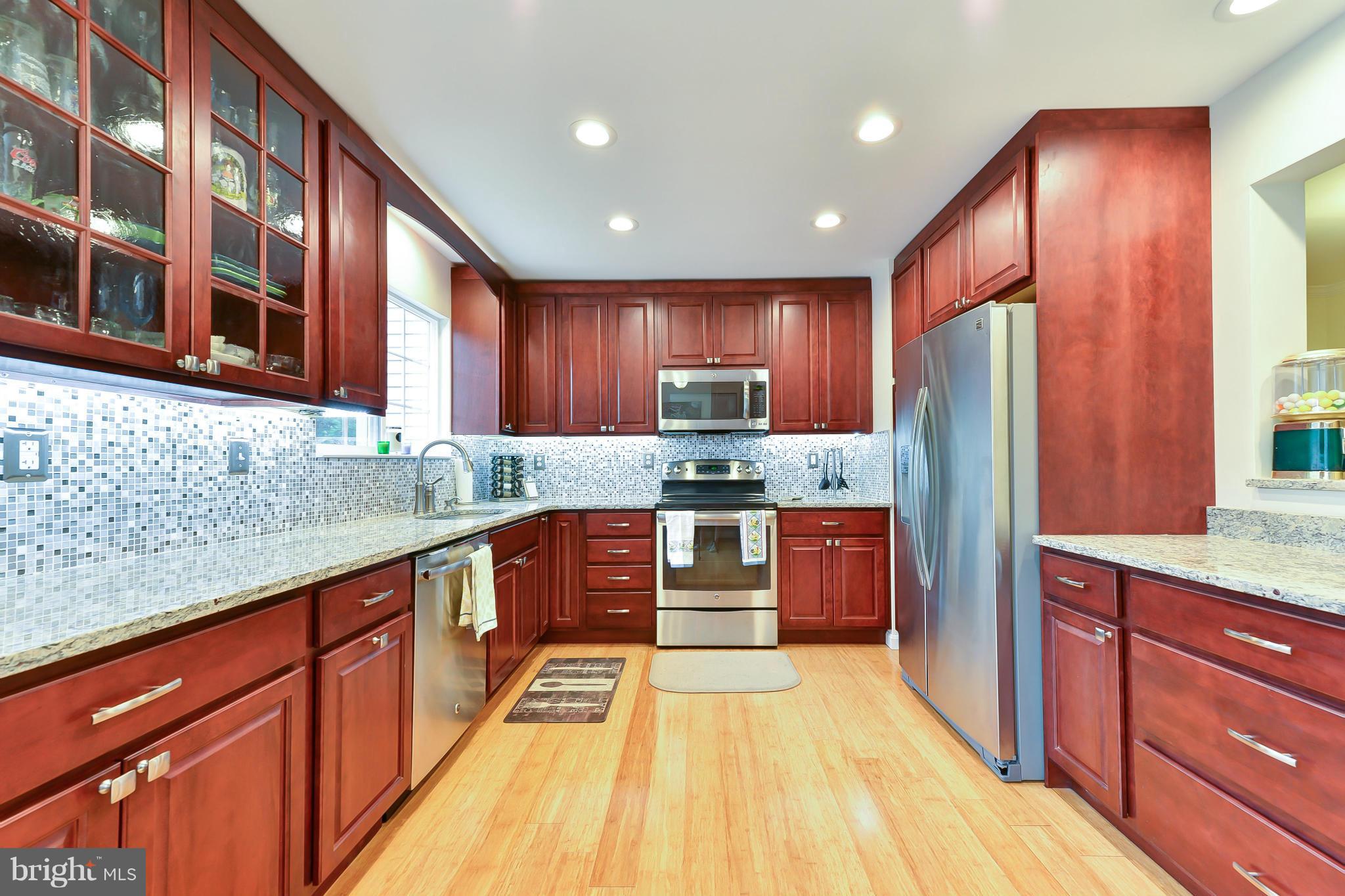 a large kitchen with stainless steel appliances wooden cabinets a stove and a sink