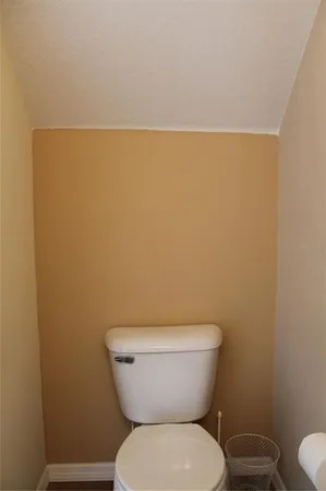 a white toilet sitting next to a white wall