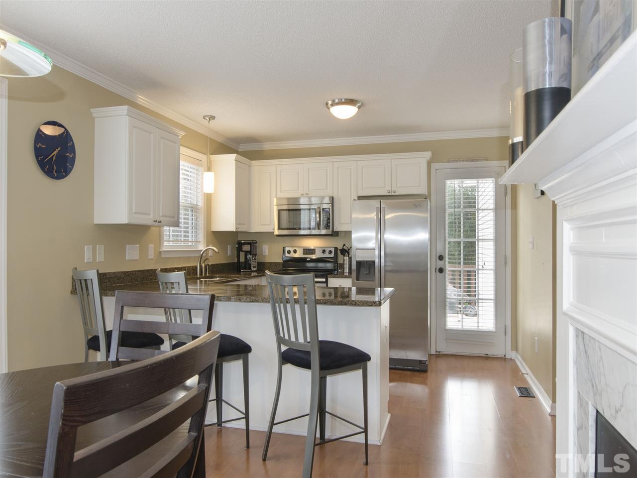 124 Fieldspring Lane Raleigh, NC 27606 - Photo 10 of 24 a kitchen with stainless steel appliances kitchen island granite countertop a refrigerator a stove a sink dishwasher with a dining table and chairs