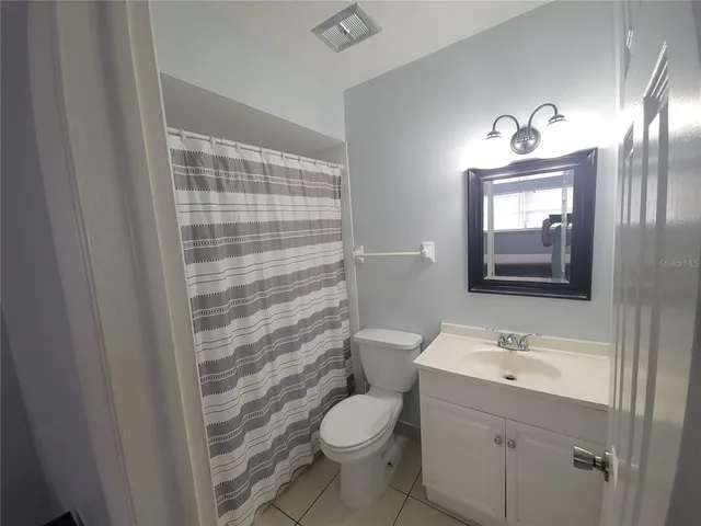 a bathroom with a toilet a sink a mirror a window and vanity