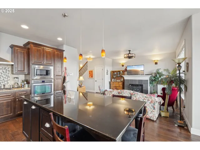 a kitchen with stainless steel appliances kitchen island granite countertop a sink dishwasher a dining table and chairs with wooden floor