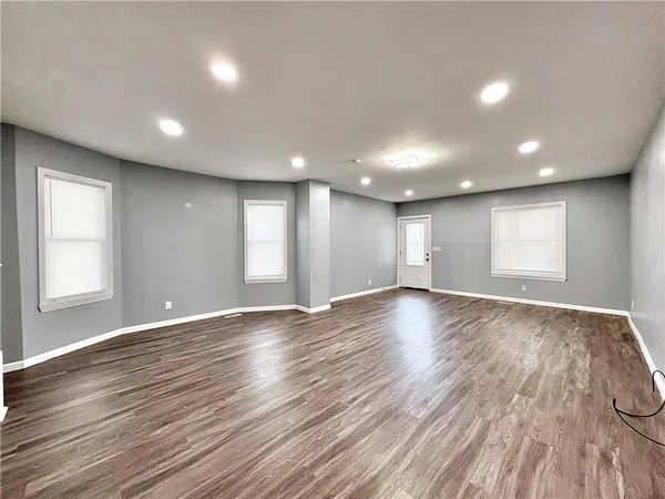 an empty room with wooden floor and windows
