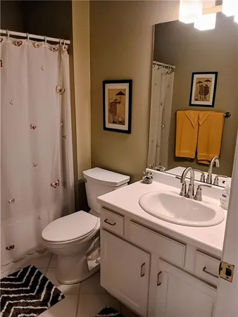a bathroom with a sink a toilet a mirror and shower curtain