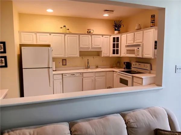a kitchen with stainless steel appliances granite countertop a refrigerator sink and white cabinets