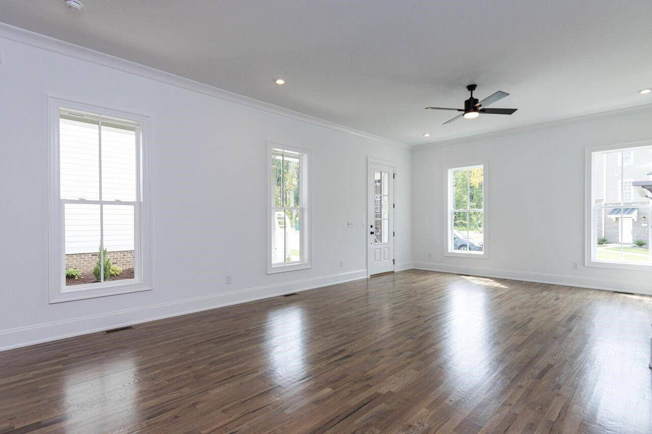 1108 Kentlands Drive Durham, NC 27713 - Photo 7 of 49 an empty room with wooden floor chandelier fan and windows