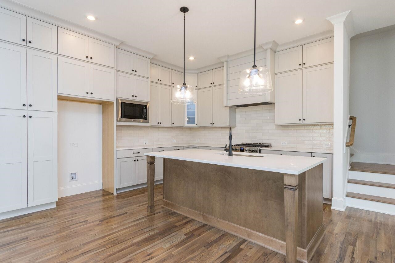 1108 Kentlands Drive Durham, NC 27713 - Photo 8 of 49 a kitchen with kitchen island a sink stove a refrigerator and white cabinets with wooden floor