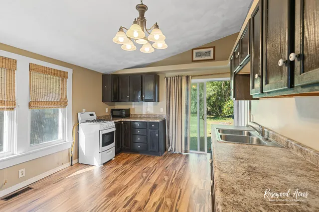 a open kitchen with a refrigerator a stove top oven a sink and dishwasher with wooden floor