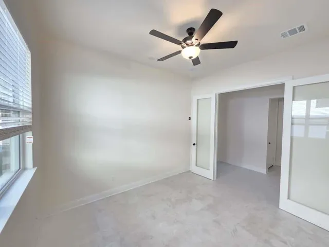 an empty room with windows and fan