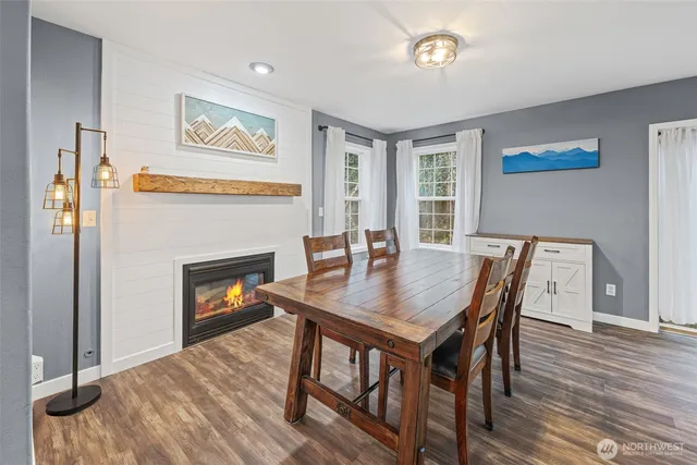 a view of a dining room with furniture a fireplace and wooden floor