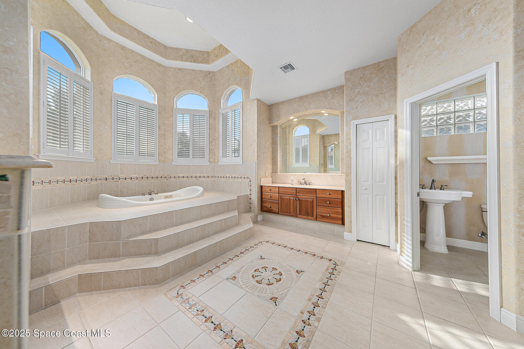 425 Baytree Drive Melbourne, FL 32940 - Photo 23 of 53 a bathroom with a tub a double vanity sink and a large mirror