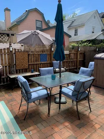 a view of a patio with a table chairs and a small yard