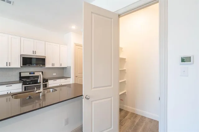 a kitchen with stainless steel appliances a refrigerator and white cabinets