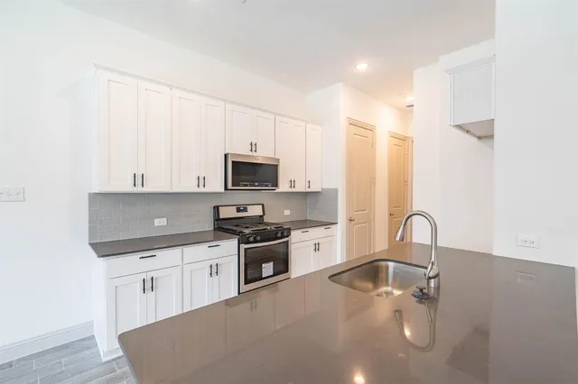 a kitchen with stainless steel appliances granite countertop a sink a stove and a microwave