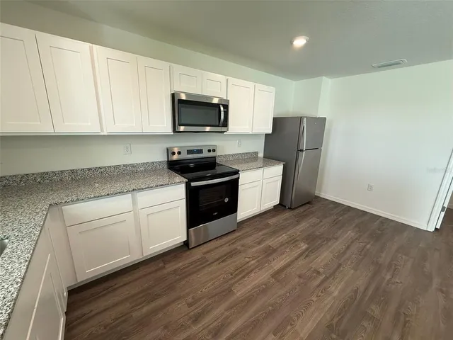 a kitchen with stainless steel appliances granite countertop a stove a sink and a microwave