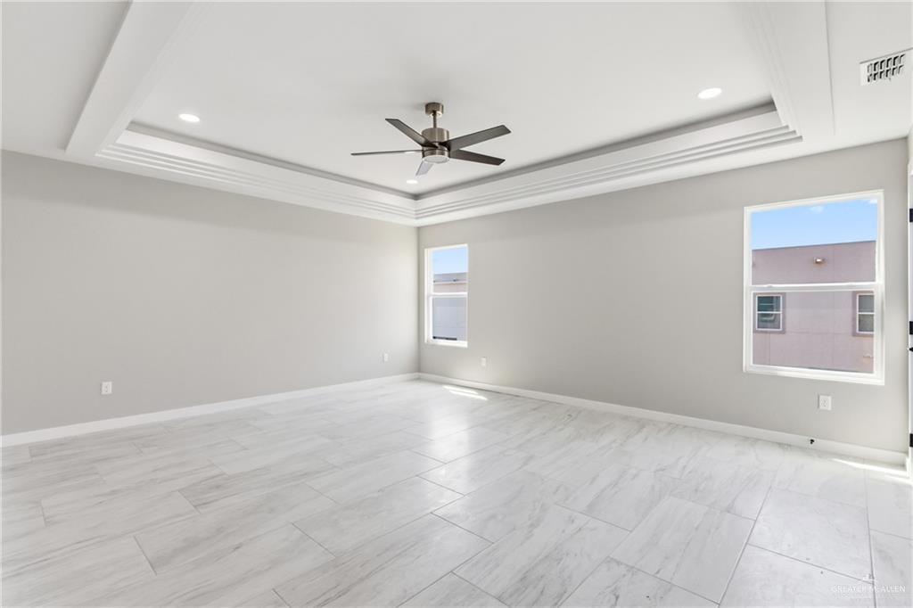2206 Corales Street Mission, TX 78573 - Photo 8 of 23 The spacious room features large windows, light-colored tile flooring, and a tray ceiling with recessed lighting and a ceiling fan