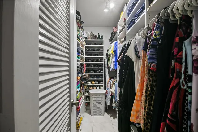 a view of walk in closet with clothes and shoes