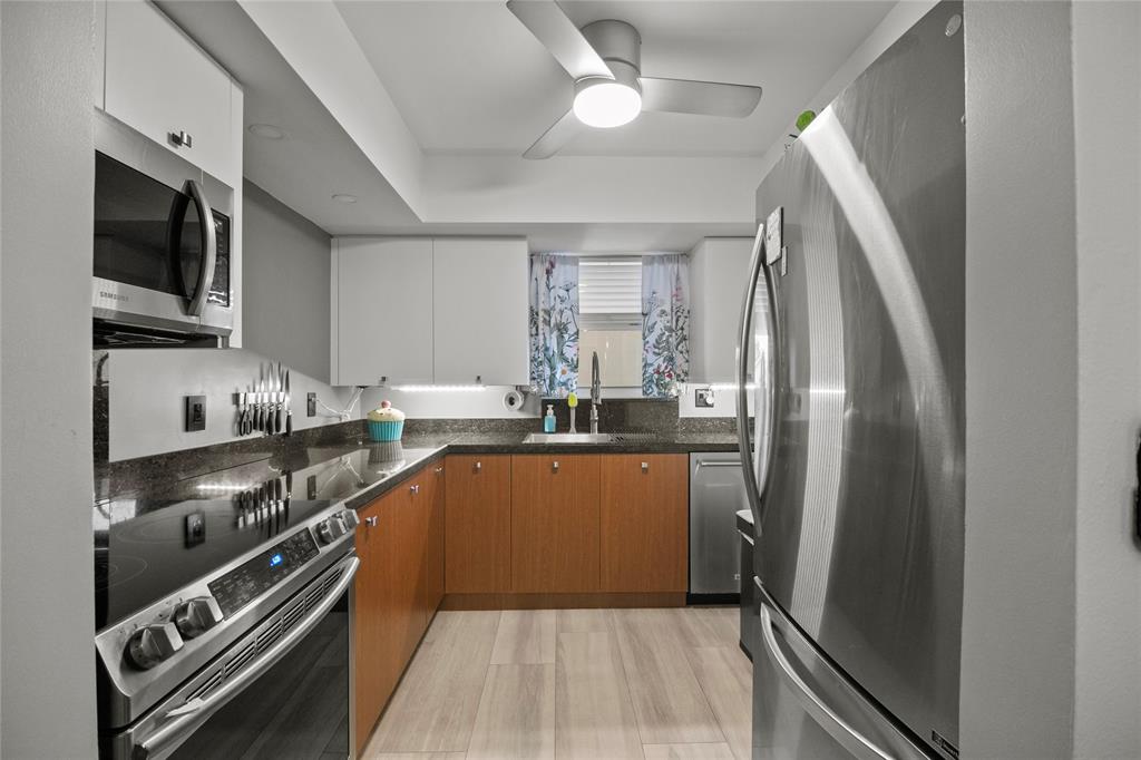 2141 Northeast 68th Street, Unit 107 Fort Lauderdale, FL 33308 - Photo 6 of 20 a kitchen with stainless steel appliances granite countertop a refrigerator a stove and a sink