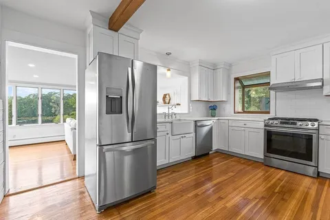 a kitchen with a refrigerator stove and wooden floor