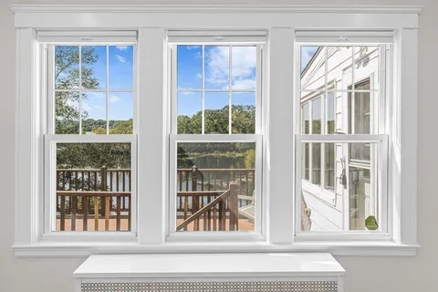 a view of an entryway with wooden floor leading to a furnished livingroom and windows