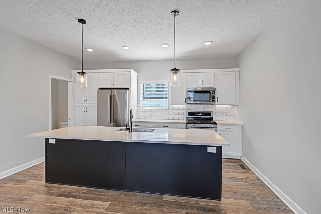3601 Bailey Avenue Cleveland, OH 44113 - Photo 6 of 22 Kitchen featuring pendant lighting, stainless steel appliances, white cabinets, and hardwood / wood-style flooring