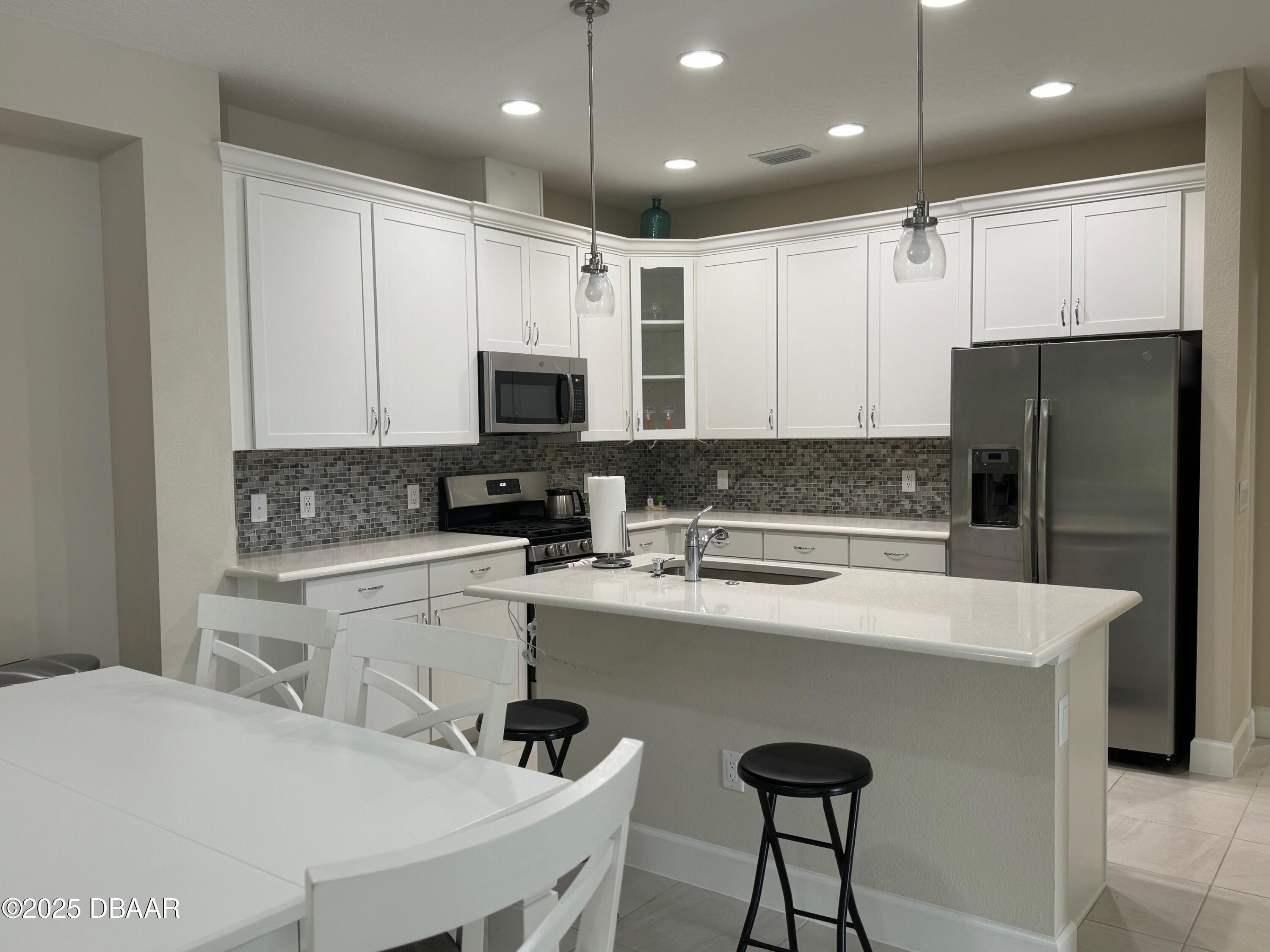 1016 Sea Shell Court Daytona Beach, FL 32124 - Photo 19 of 25 a kitchen with kitchen island a refrigerator stove and microwave