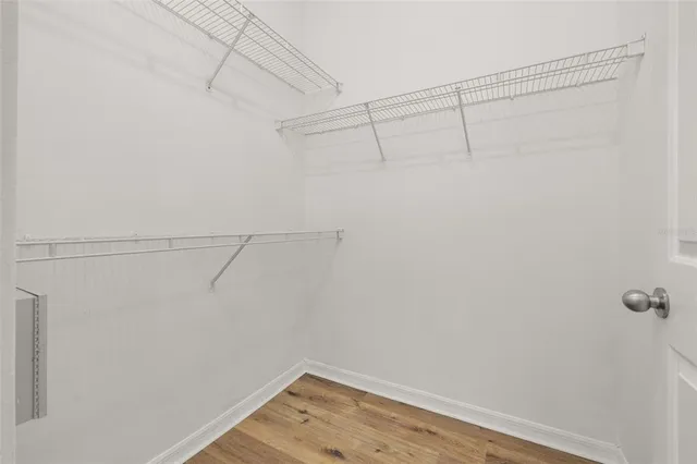 an empty room with wooden floor ceiling fan and windows