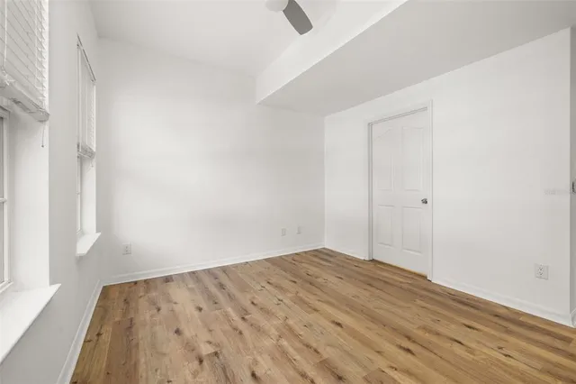 a view of empty room with wooden floor and fan