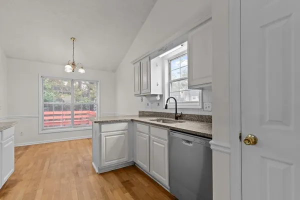 a kitchen with stainless steel appliances granite countertop a sink cabinets wooden floor and a window