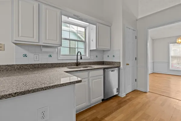 a kitchen with granite countertop a sink stainless steel appliances white cabinets and a window