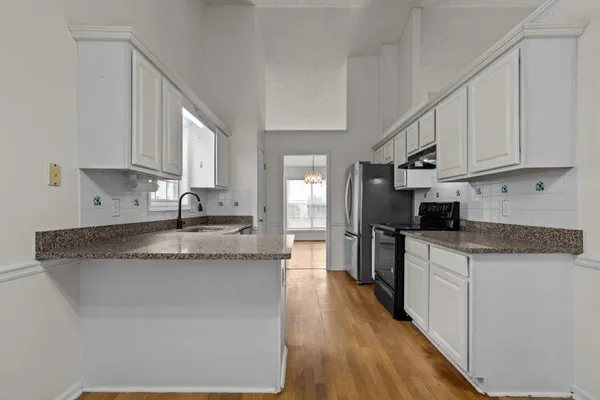a kitchen with stainless steel appliances granite countertop a stove a sink and white cabinets