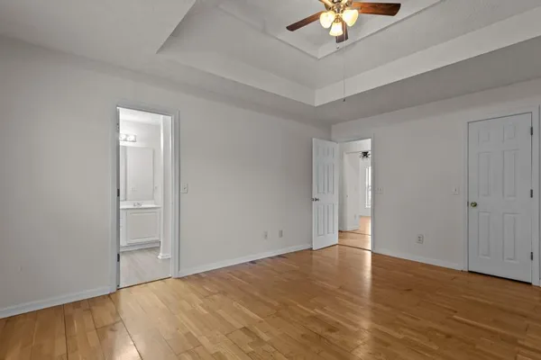 a view of an empty room with chandelier fan and wooden floor