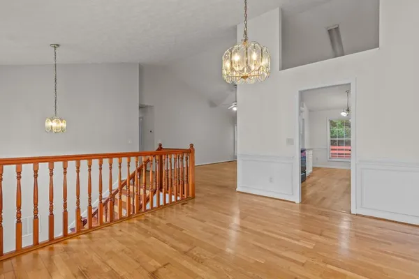 a view of a hallway with wooden floor and chandelier