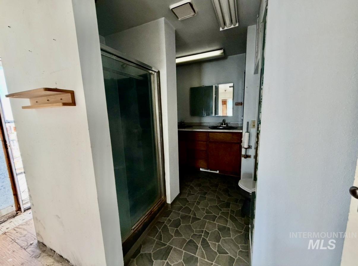 2454 Riverside Drive Clarkston, WA 99403 - Photo 12 of 23 Bathroom with patterned floor tile, glass-enclosed shower, wood-finish vanity, and wall-mounted mirror