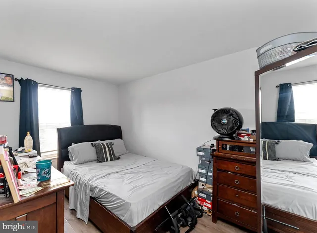 a bedroom with a bed a mirror on dresser and a large mirror