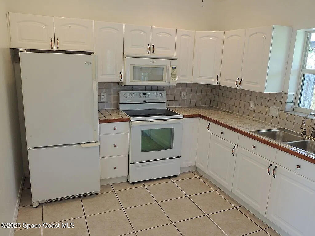206 4th Avenue Indialantic, FL 32903 - Photo 14 of 43 a kitchen with white cabinets and white appliances