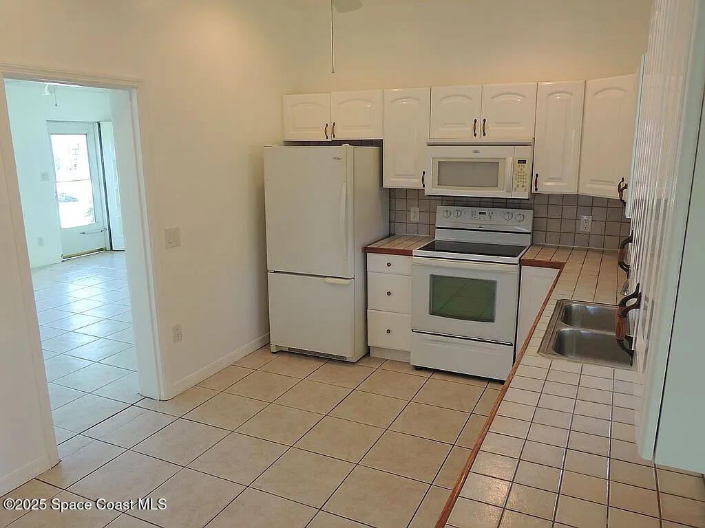 206 4th Avenue Indialantic, FL 32903 - Photo 16 of 43 a kitchen with white cabinets a sink a stove and a refrigerator