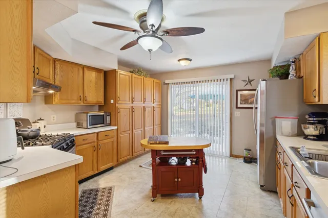 a large kitchen with stainless steel appliances a stove a refrigerator a sink dishwasher a dining table and chairs with wooden floor