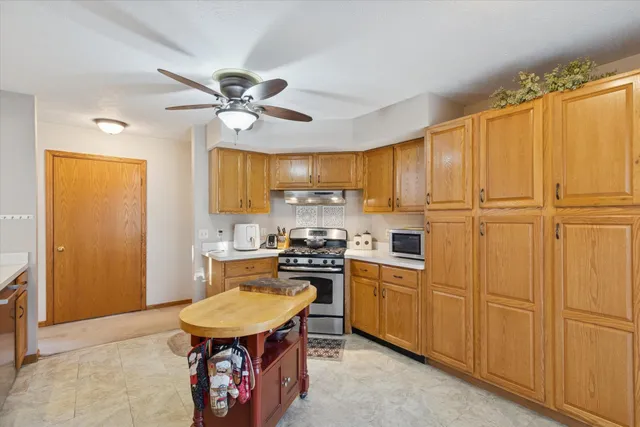 a kitchen with stainless steel appliances a stove a refrigerator a sink a stove with white cabinets and wooden floor